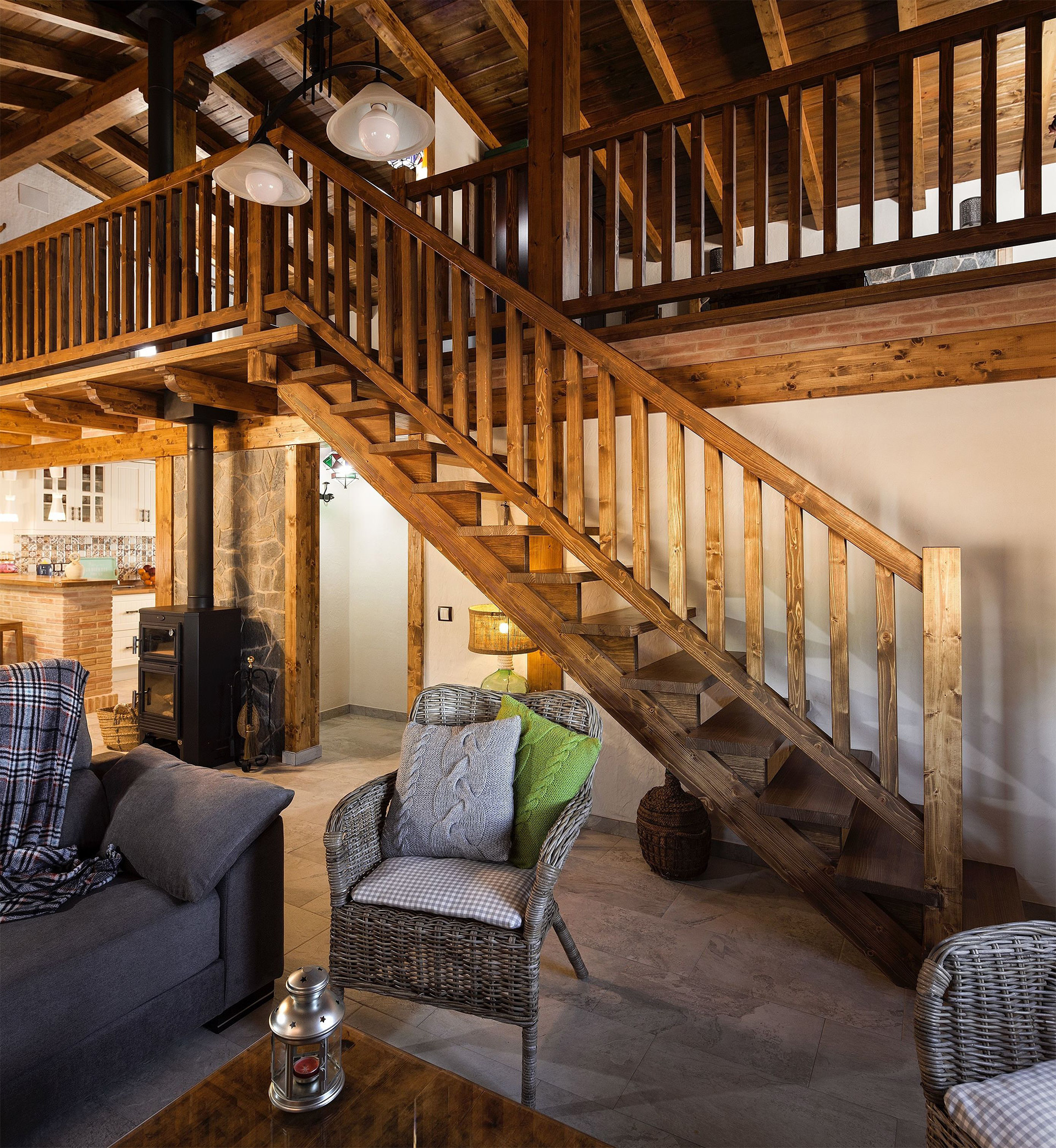 Interior de la casa, vista desde el salón. Vemos la subida de la escalera todo en madera y la segunda planta abierta. Resaltando la gran bóveda de madera y sus grandes pilares principales de madera maciza.